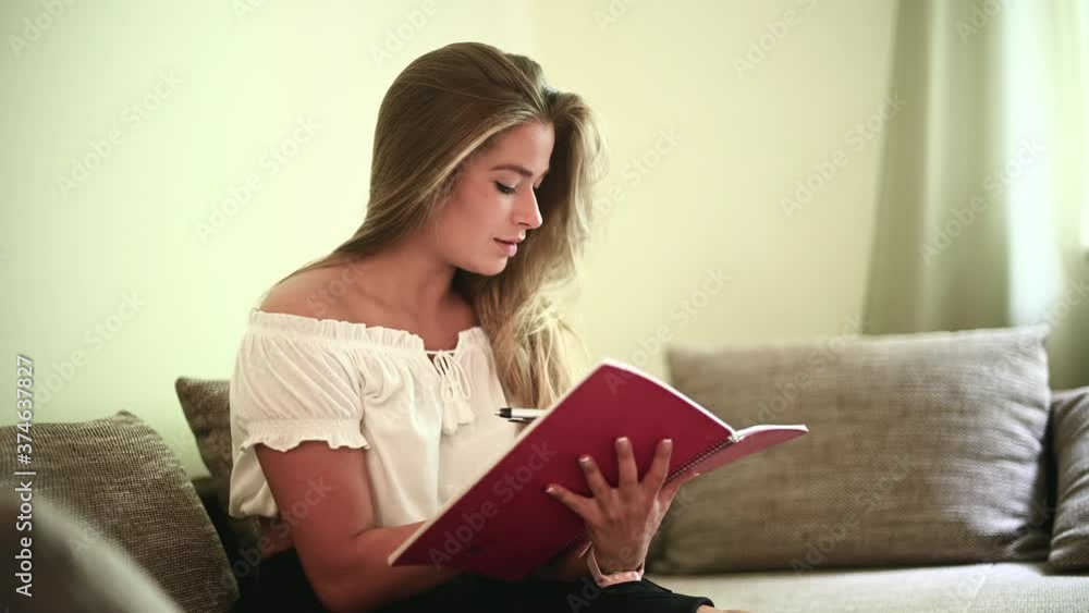 Young woman studying sitting on her sofa in her flat Young woman studying sitting on her sofa in her flat