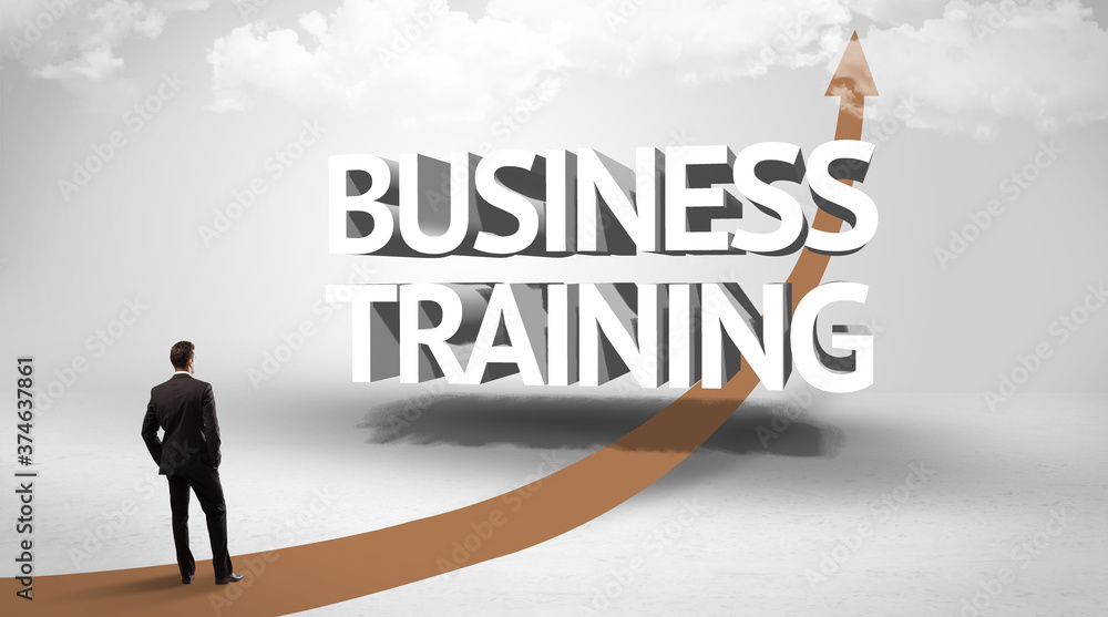 Rear view of a businessman standing in front of BUSINESS TRAINING inscription, successful business concept Rear view of a businessman standing in front of BUSINESS TRAINING inscription, successful business concept
