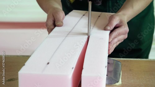 An female worker cutting foam rubber for the production of a sofa in a furniture factory. 4K