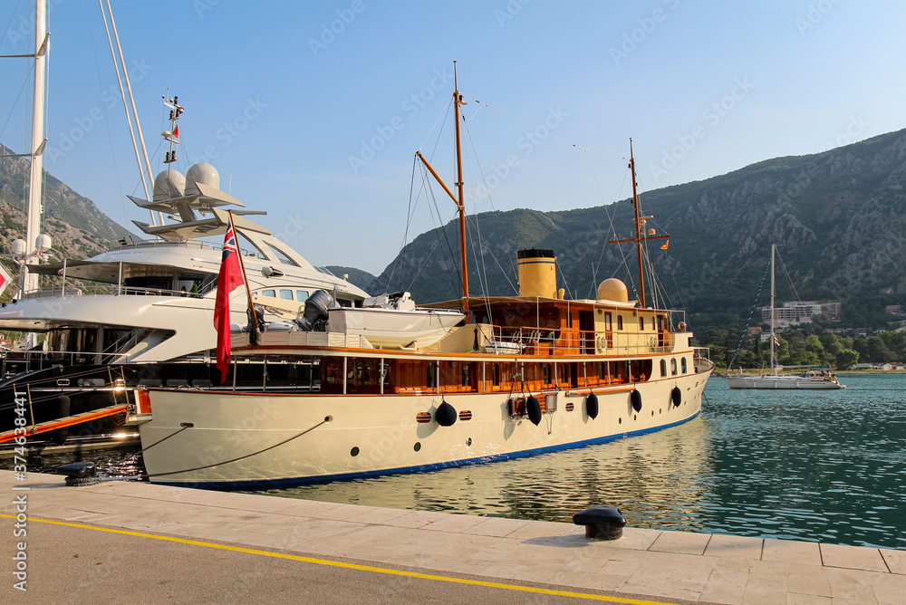 Fototapeta premium An old yacht moored at the harbour at the Old Town of Kotor, at the bay of Kotor