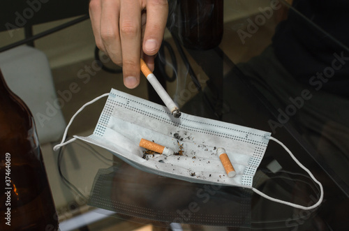 Person smoking cigarette and using face mask as an ashtray.