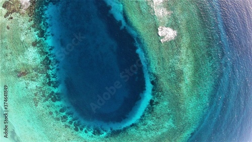 View from above of the beautiful play of blue tones, emerald green and turquoise of the Caribbean Sea off Grenada's coast. It is reminiscent of a blue hole in the sea. photo