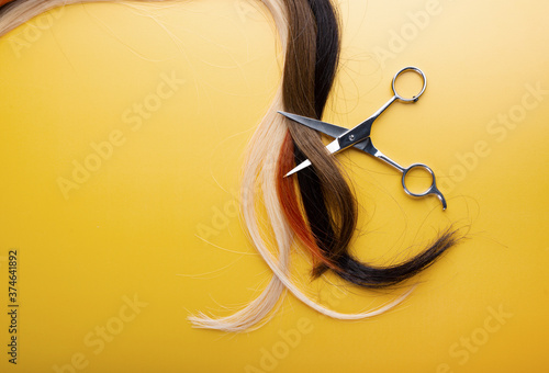 Professional hairstyle scissors with strands of hair isolated on yellow background