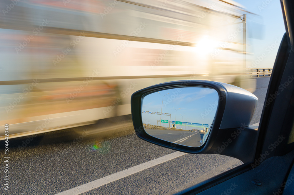 Truck moving on high speed on motorway, blurred view from car window. Road traffic