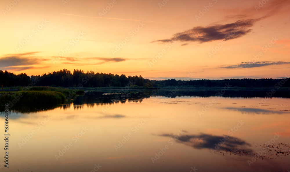 Bright beautiful landscape, orange sunset sky over a lake in the forest, reflections in the water