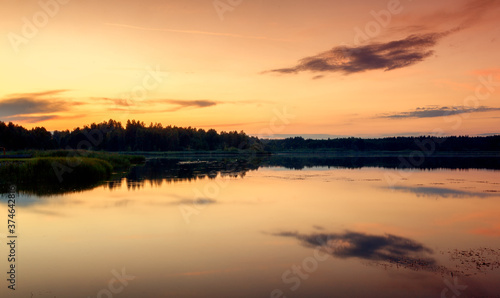 Bright beautiful landscape, orange sunset sky over a lake in the forest, reflections in the water © olezzo