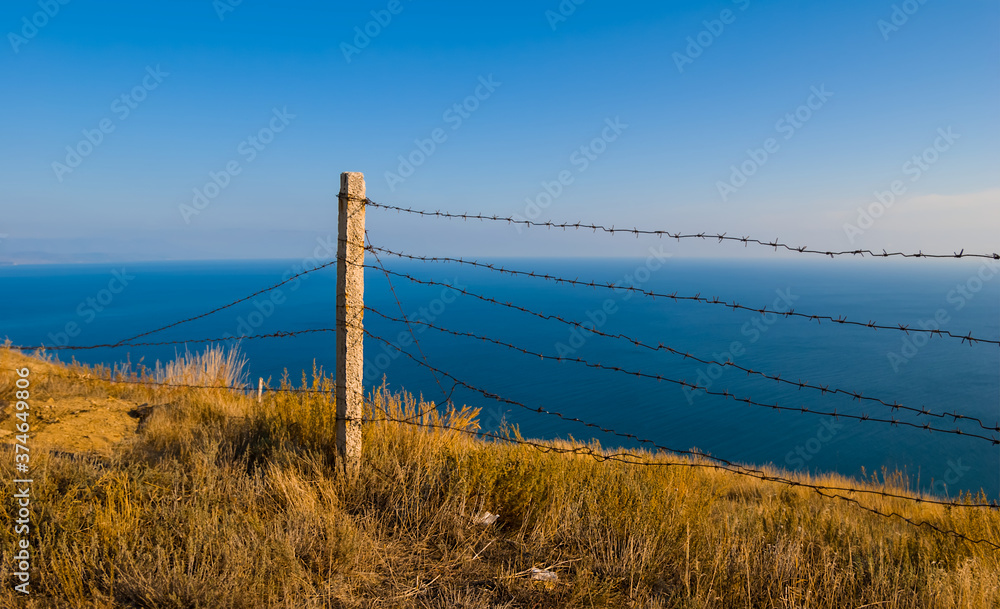 barbed wire on a mount slope above a sea bay