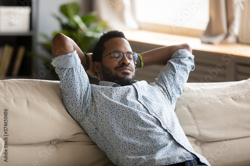 Wallpaper Mural Peaceful African American man wearing glasses relaxing on cozy couch with hands