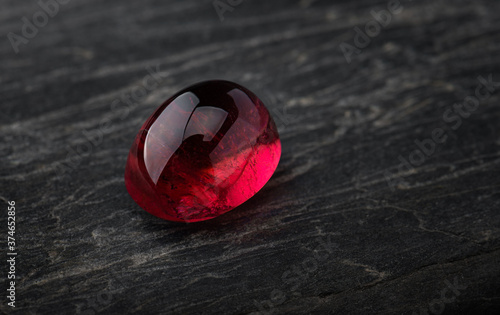 Foto Red ruby gemstone with dark rock.