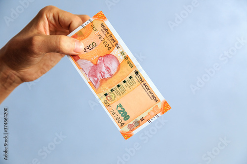 the hand holds 200 rupees bill