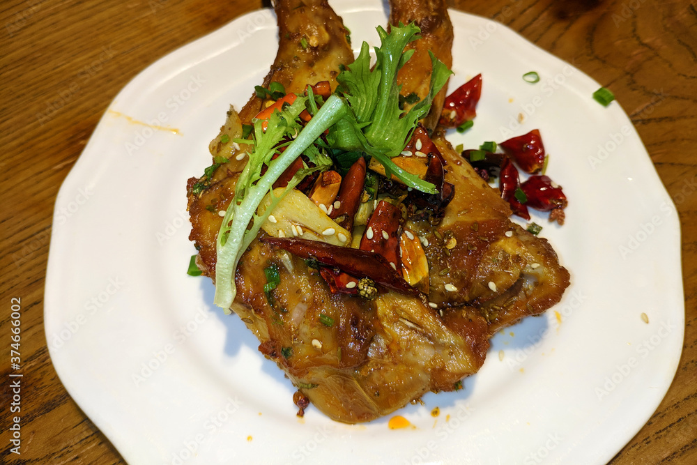 two fresh fried rabbit's legs with vegetables and peppers on the white plate two fresh fried rabbit's legs with vegetables and peppers on the white plate