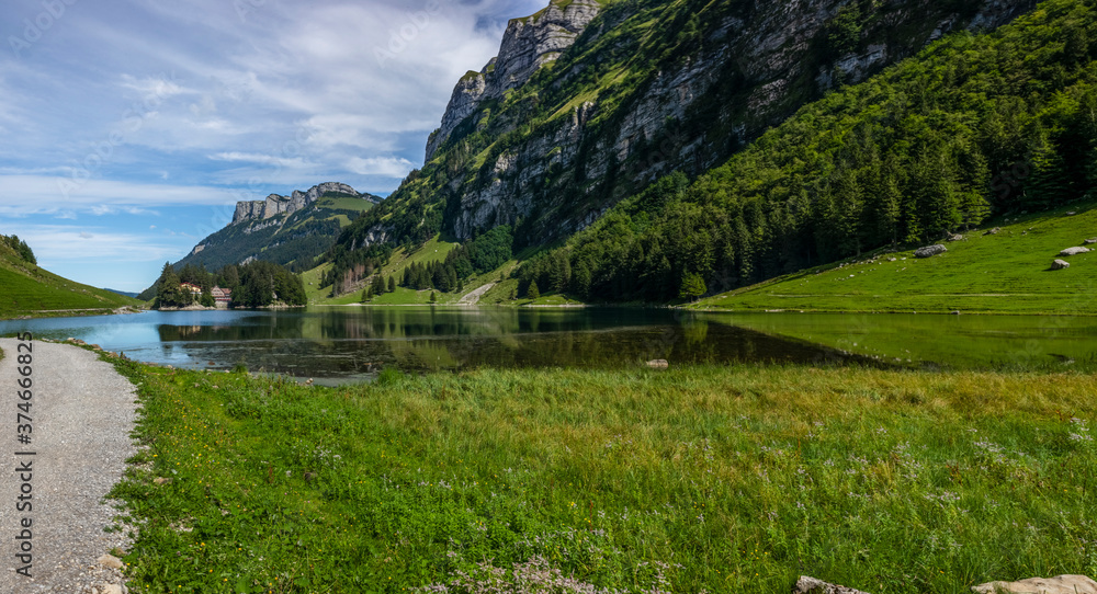 The view of the Seealpsee lake in Appenzell, Switzerland sitting betweeen the tall peaks of the Alpstein mountain range