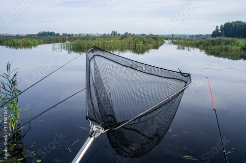 Fishing landing net with coarse nylon net on a forest lake