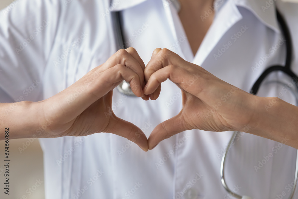 Close up young woman wearing white uniform with stethoscope, doctor showing heart gesture, cardiologist therapist physician gp recommending regular medical checkup, healthcare concept Close up young woman wearing white uniform with stethoscope, doctor showing heart gesture, cardiologist therapist physician gp recommending regular medical checkup, healthcare concept