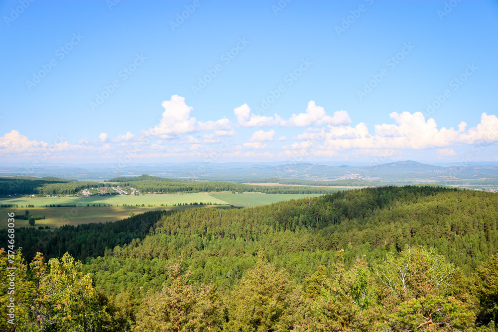 View of villages, towns and pine forests from the Chashkovsky ridge. Ural mountains. Eco-tourism and hiking concept. View of villages, towns and pine forests from the Chashkovsky ridge. Ural mountains. Eco-tourism and hiking concept.