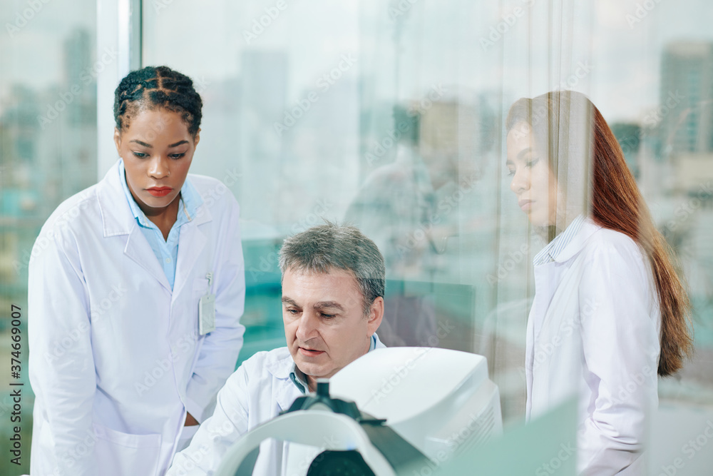 Group of serious ophthalmology clinic specialists discussing results of ocular fundus examination Group of serious ophthalmology clinic specialists discussing results of ocular fundus examination