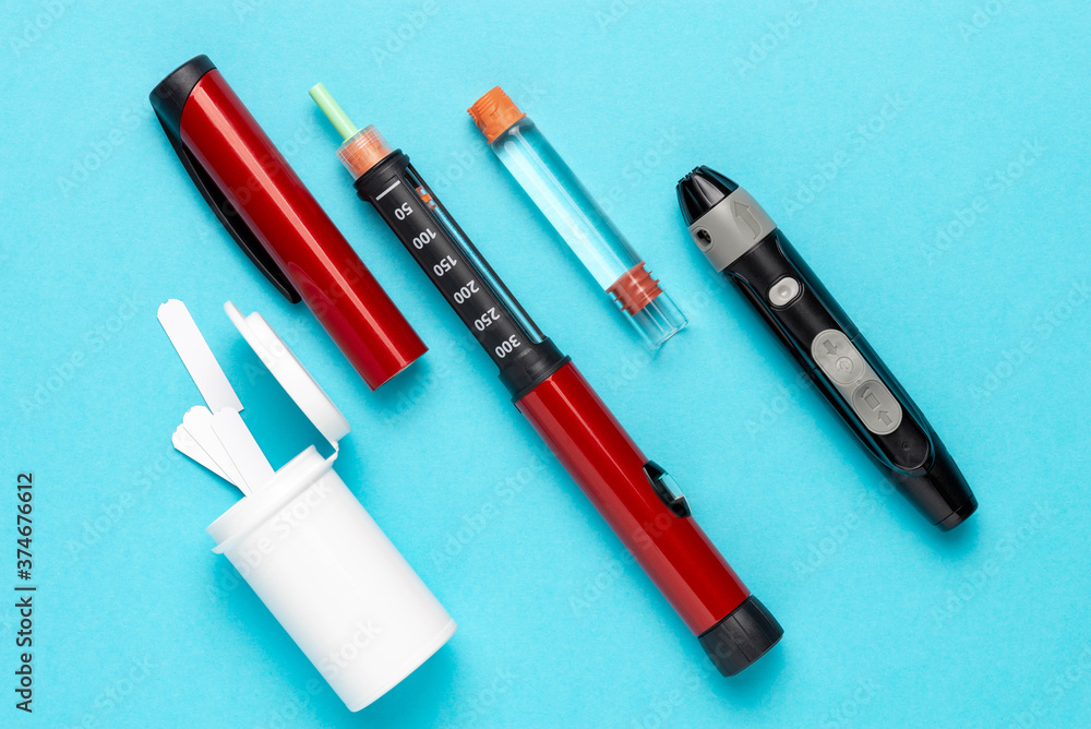 Diabetic set of lancet with spare needles, strips, box of spare strips, pen injector, spare insulin and pen needles on a blue background Diabetic set of lancet with spare needles, strips, box of spare strips, pen injector, spare insulin and pen needles on a blue background