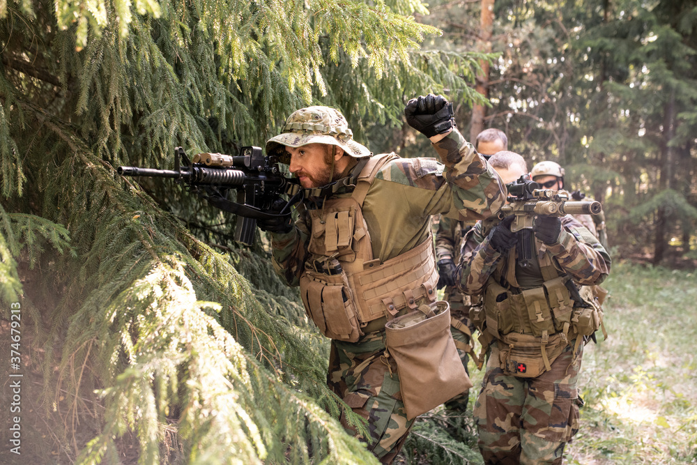 Fototapeta premium Military leader looking though rifle scope and preparing his team for attack