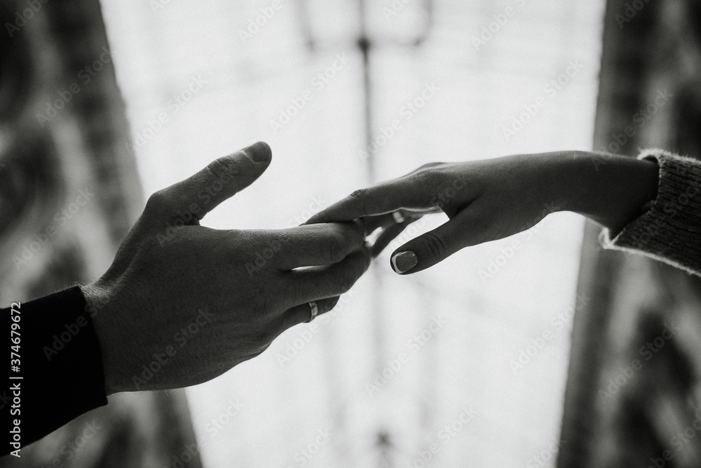 the man's hand reaches for the woman's hand on a blurred background.
