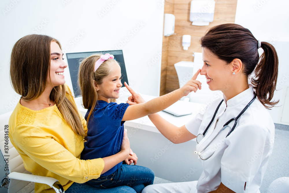Obraz premium Friendly pediatrician having fun with her child patient at the hospital. Consultation, kid health.