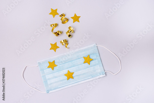 Gold Confetti in Shape of Star Protective Face Mask on Blue Background New Year 2021 Celebration Concept Top view Flat lay Holidays photo