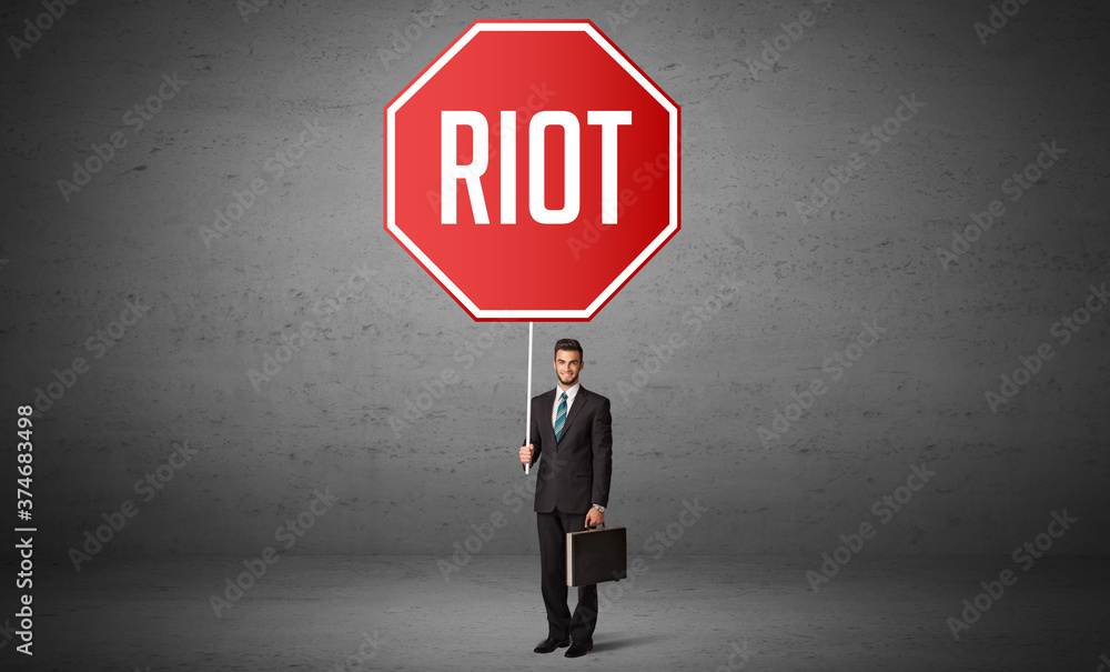 Young business person holding road sign with RIOT inscription, new rules concept Young business person holding road sign with RIOT inscription, new rules concept