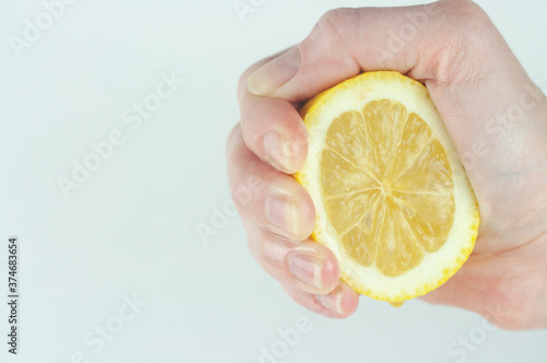 a woman 's hand squeezes a lemon on a white background