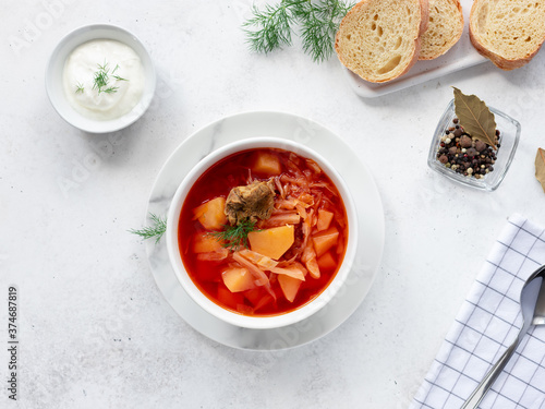 homemade borscht with beets, cabbage, potatoes and meat, served with sour cream and herbs. Traditional Russian Ukrainian soup. top view. White background.