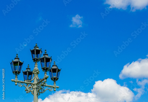 A tall pole with antique lanterns on the street during the day.