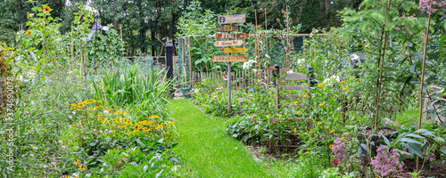 Barneveld, Netherlands- August 23, 2020: Cozy little garden with vegetables, colorful flowers,all kinds of decorations and signs with DUtch text