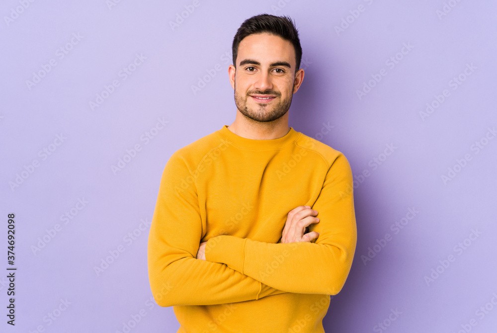 Young caucasian man isolated on purple background who feels confident, crossing arms with determination. Young caucasian man isolated on purple background who feels confident, crossing arms with determination.