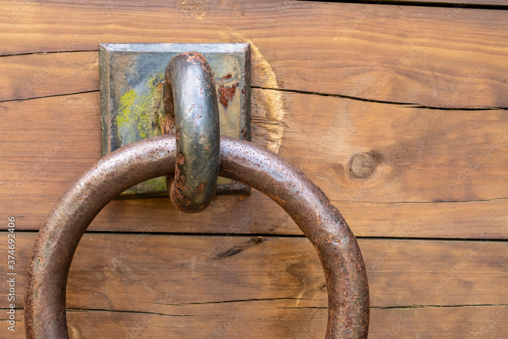 Wooden old cracked shabby plank with rusty door ring Wooden old cracked shabby plank with rusty door ring
