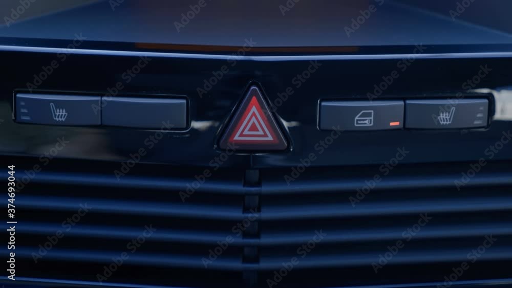 The driver's finger presses the button to close all the doors of the car on the shiny black dashboard. The button is highlighted in orange. Closeup The driver's finger presses the button to close all the doors of the car on the shiny black dashboard. The button is highlighted in orange. Closeup
