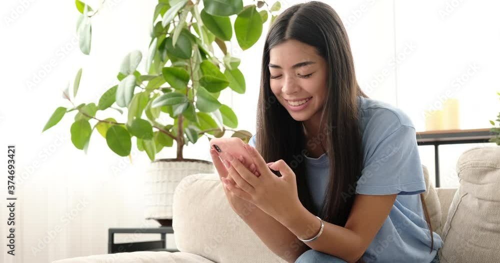 Happy woman text messaging using mobile phone at home Happy woman text messaging using mobile phone at home