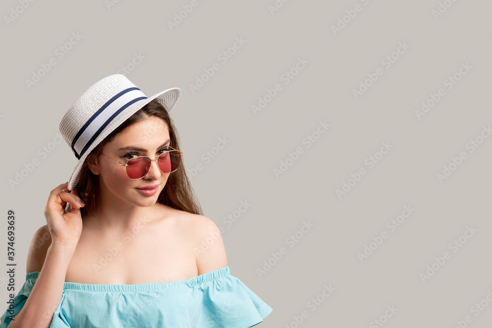 Holiday trip. Summer outfit. Smiling stylish woman in off-the-shoulder blue dress white hat and sunglasses looking at camera isolated on neutral copy space. Travel agency. Sun protection accessories Holiday trip. Summer outfit. Smiling stylish woman in off-the-shoulder blue dress white hat and sunglasses looking at camera isolated on neutral copy space. Travel agency. Sun protection accessories