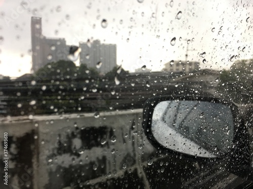 Raindrops on the car window and side mirror during the journey on a rainy day