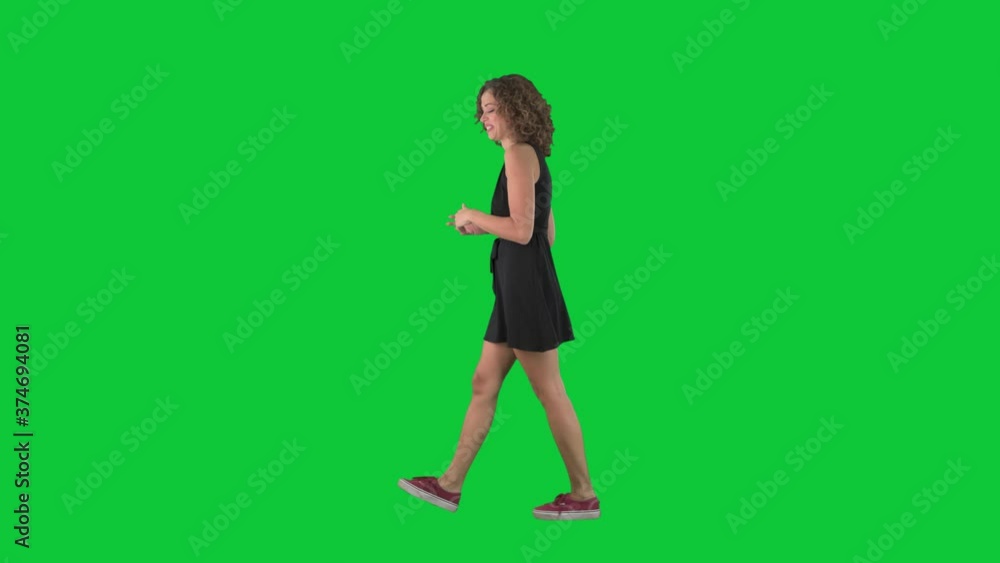 Happy young stylish woman walking and speaking gesticulate. Full body side view on green screen chroma key background. Happy young stylish woman walking and speaking gesticulate. Full body side view on green screen chroma key background.