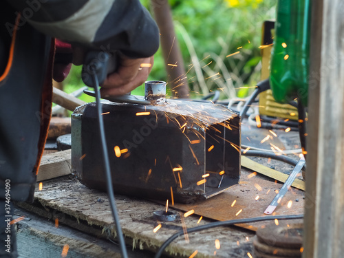 a man handles metal with an angle grinder. sparks from metal.