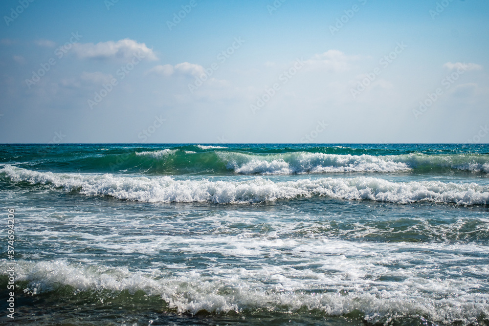 Beautiful sea waves splash with white foam on a blue ocean surface background.