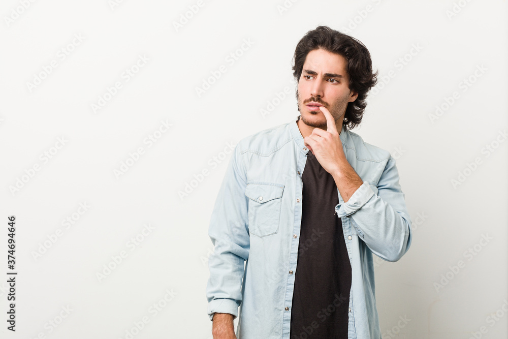 Young handsome man against a white background looking sideways with doubtful and skeptical expression. Young handsome man against a white background looking sideways with doubtful and skeptical expression.