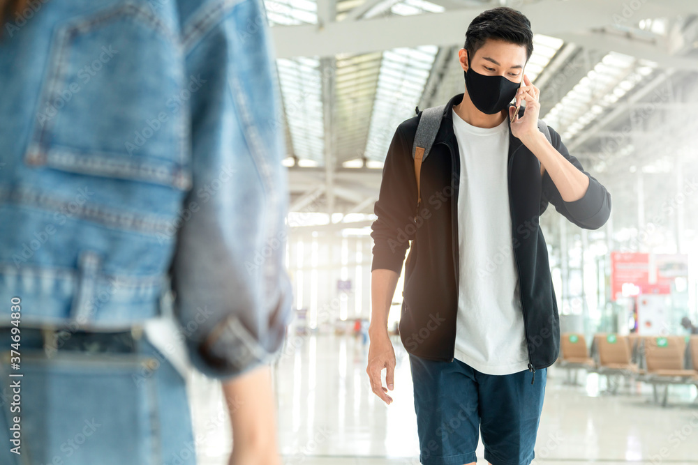 attractive smart asian male treveller casual cloth wear black protective face mask walking and hand use smartphone communication in airport terminal attractive smart asian male treveller casual cloth wear black protective face mask walking and hand use smartphone communication in airport terminal