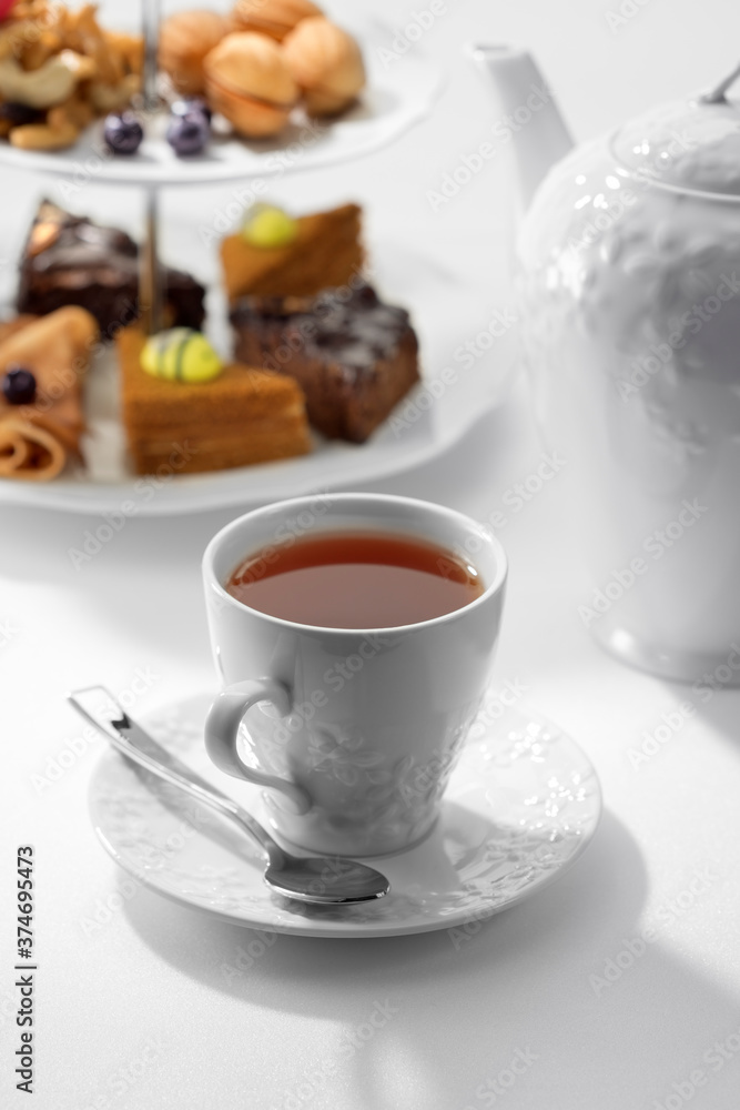 Fototapeta premium Close up view of dessert plate, china teapot and cups on white background