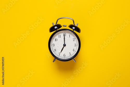 alarm clock shows 7 o'clock on a yellow background