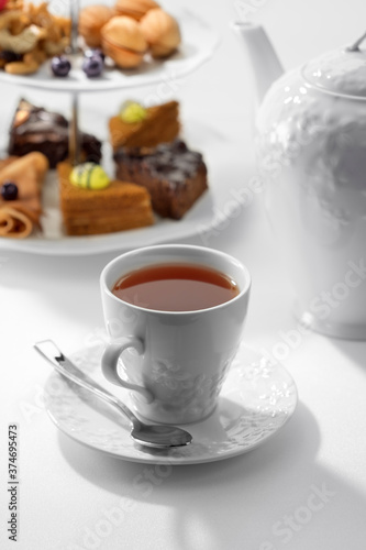 Close up view of dessert plate, china teapot and cups on white background