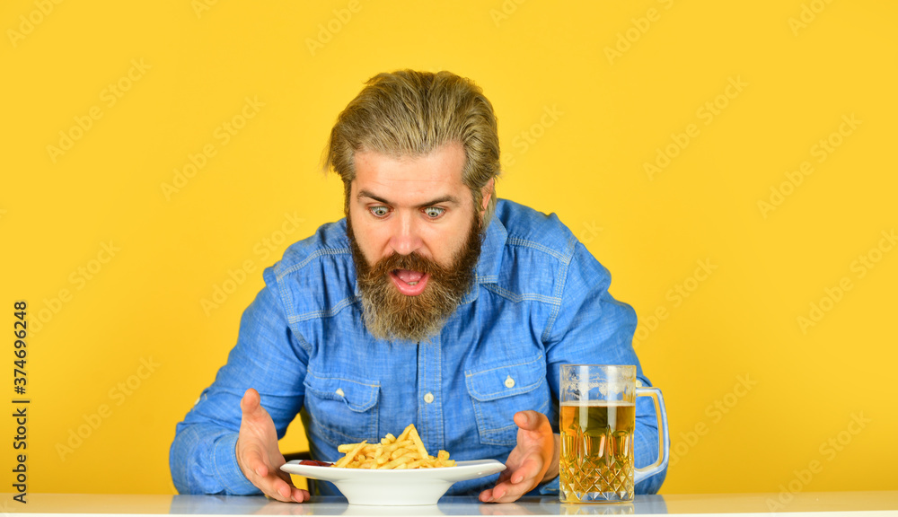 man with fast food. beer and french fries in restaurant. eating and drinking at bar. hipster relax in tavern. bearded guy having snack. lazy man enjoying fresh beer and junk food man with fast food. beer and french fries in restaurant. eating and drinking at bar. hipster relax in tavern. bearded guy having snack. lazy man enjoying fresh beer and junk food
