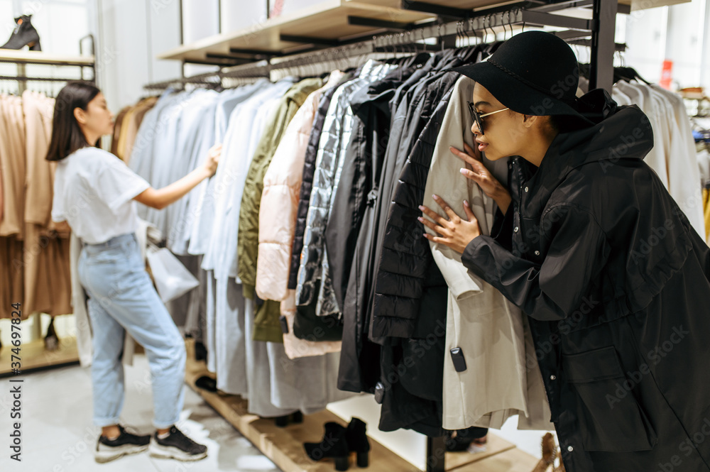 Fototapeta premium Two cute girls buying clothes in clothing store