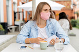 Portrait of young woman at cafe wearing face protective mask to prevent infectious diseases