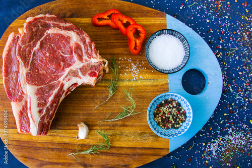 Raw beef meat on the table, spices and Rosemary, Rib eye steak ingredients. Pepper and coars salt. photo