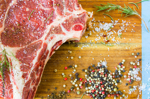 Raw beef meat on the table, spices and Rosemary, Rib eye steak ingredients. Pepper and coars salt. photo