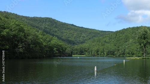 A blue sky summer day at Sherando Lake, part of the George Washington National Forest, in Virginia's Blue Ridge Mountains. Stand up paddleboard users and kayakers are seen paddling on the lake. photo